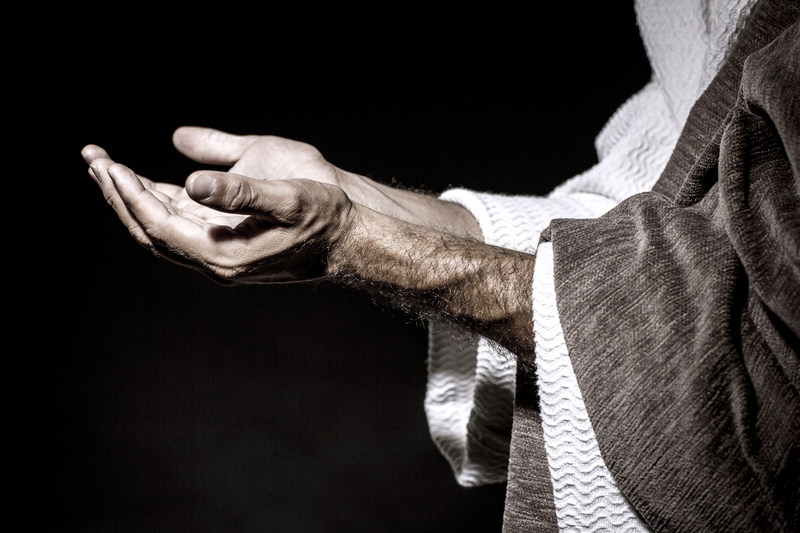 Mann in biblischen Roben hält die Hände zum Gebet auf. 